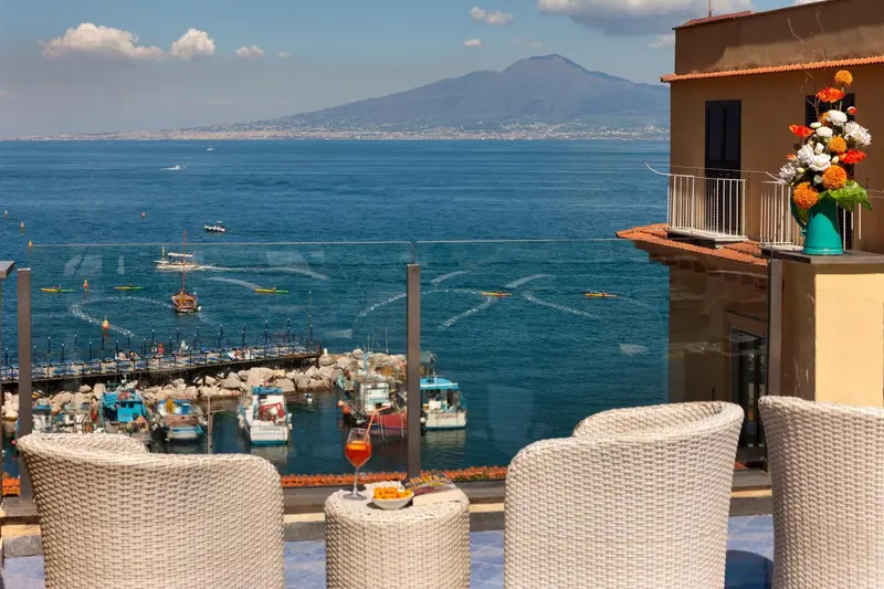 Vue sur la mer et le port depuis une terrasse ensoleillée.