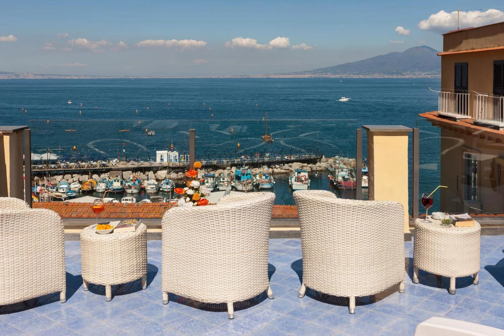 Terrasse avec mobilier d'extérieur et vue sur la mer et le port.