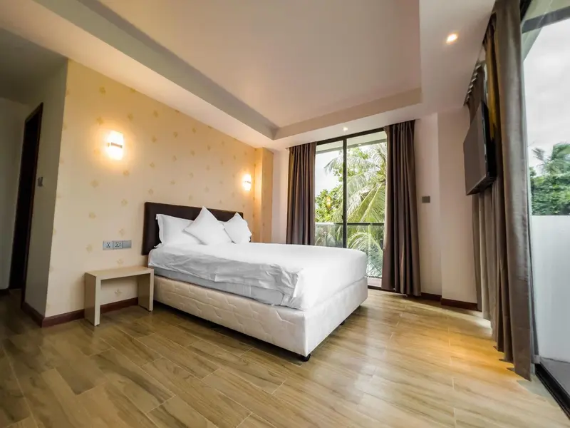 Une chambre lumineuse avec un grand lit et une baie vitrée.