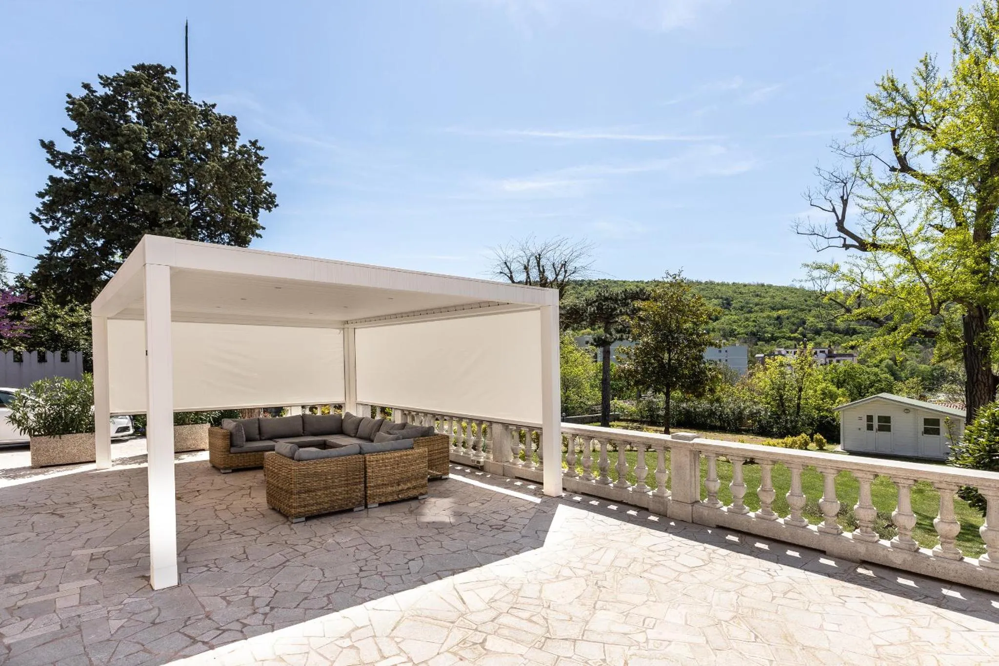 Terrasse ombragée avec mobilier de détente et vue sur la végétation.