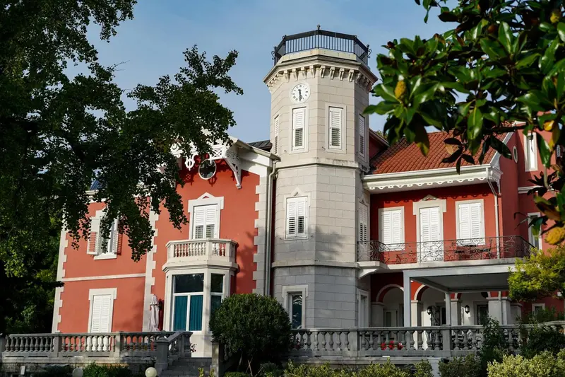 Bâtiment rouge et blanc avec une tour ornée d'une horloge.