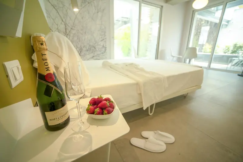 Une bouteille de champagne et des fraises sont posées sur une table de chevet dans une chambre.