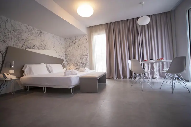 Une chambre lumineuse avec un grand lit et un coin repas.