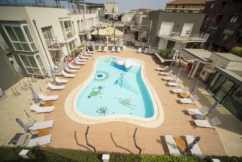 Vue aérienne d'une piscine avec transats et parasols dans un espace extérieur aménagé.
