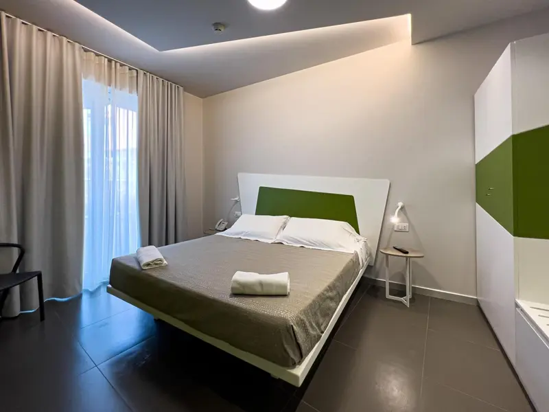 Chambre moderne avec un grand lit et un rideau beige.