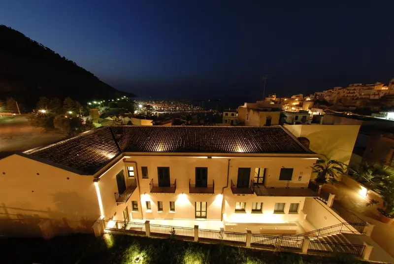 Vue nocturne d'un bâtiment éclairé surplombant une ville côtière.