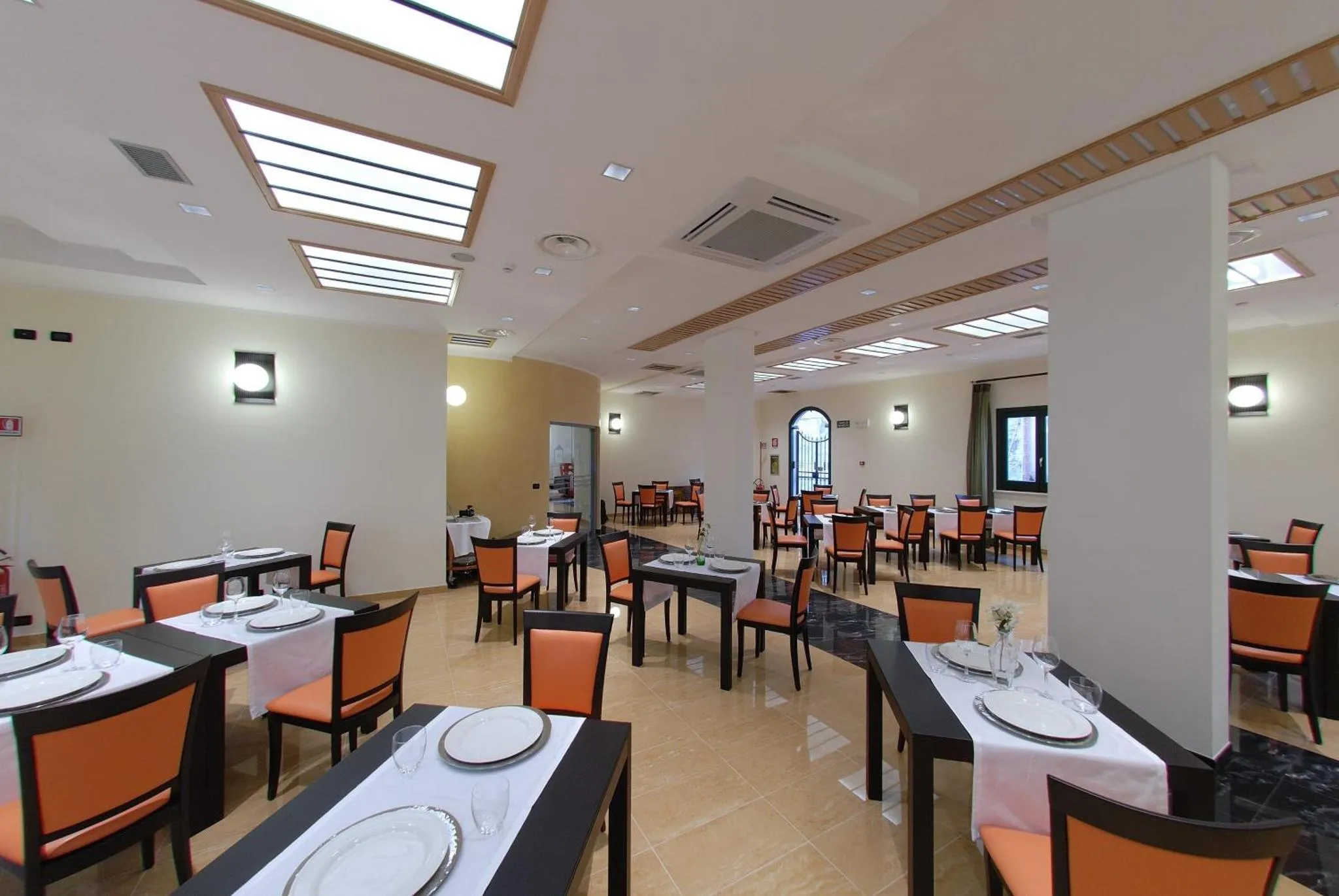 Une salle lumineuse avec des tables dressées pour un repas.