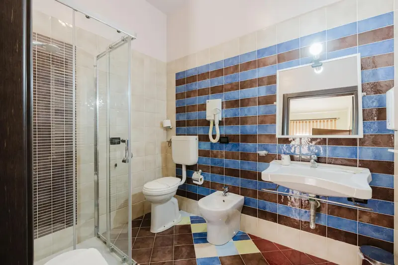 Une salle de bain lumineuse avec douche à l'italienne et carrelage coloré.