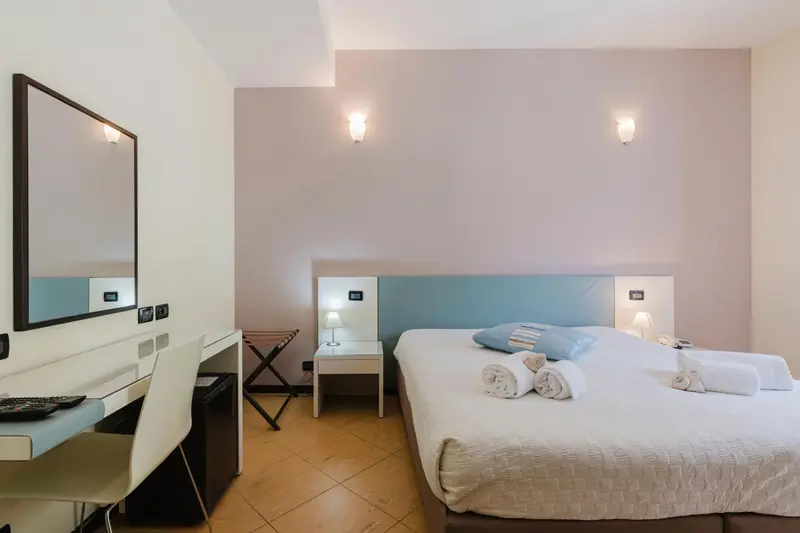 Une chambre lumineuse avec un lit double et un bureau.