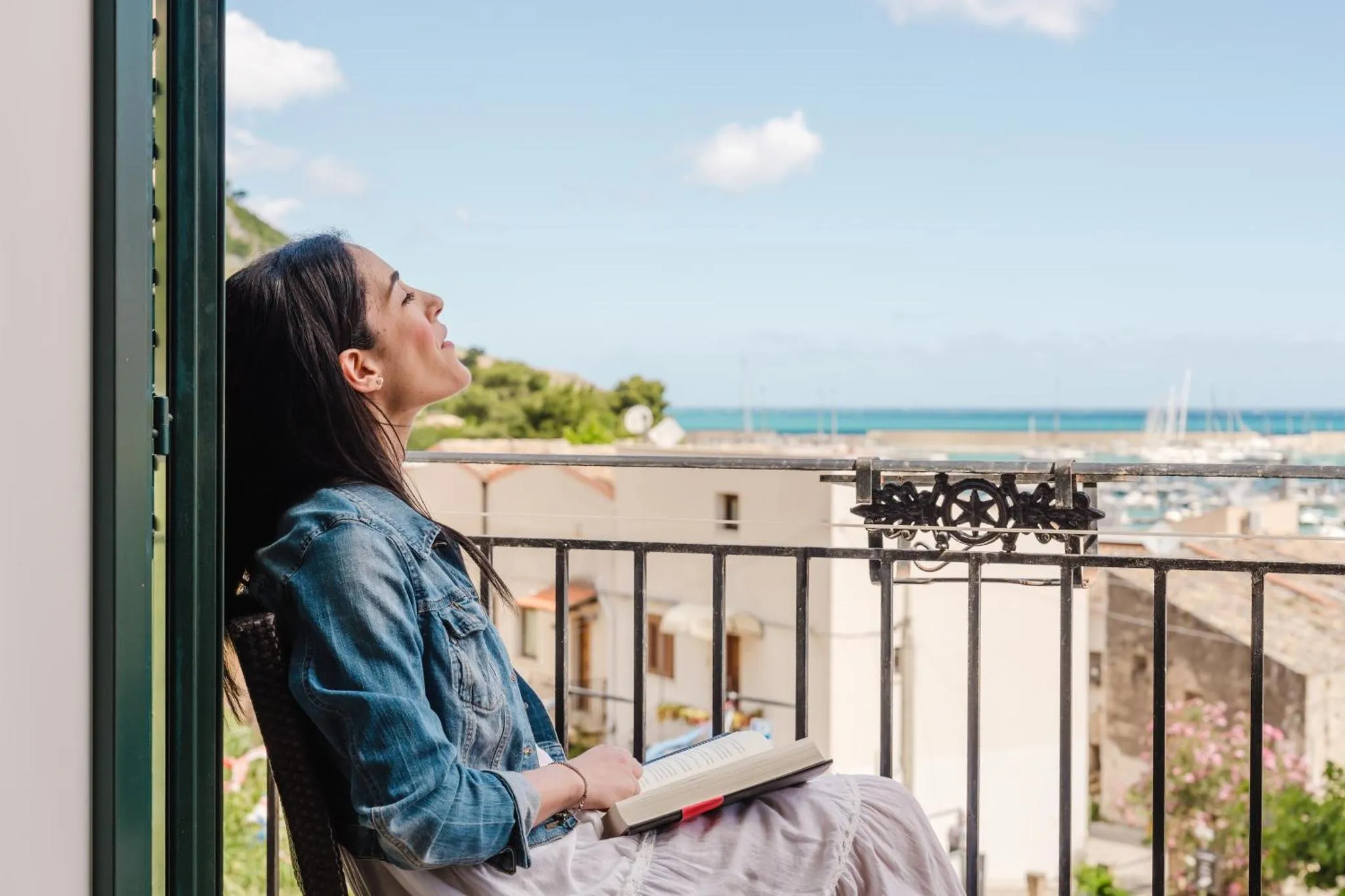 Une femme se penche sur une balustrade face à la mer.