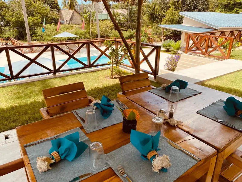Une table est dressée sur une terrasse avec une piscine en arrière-plan.