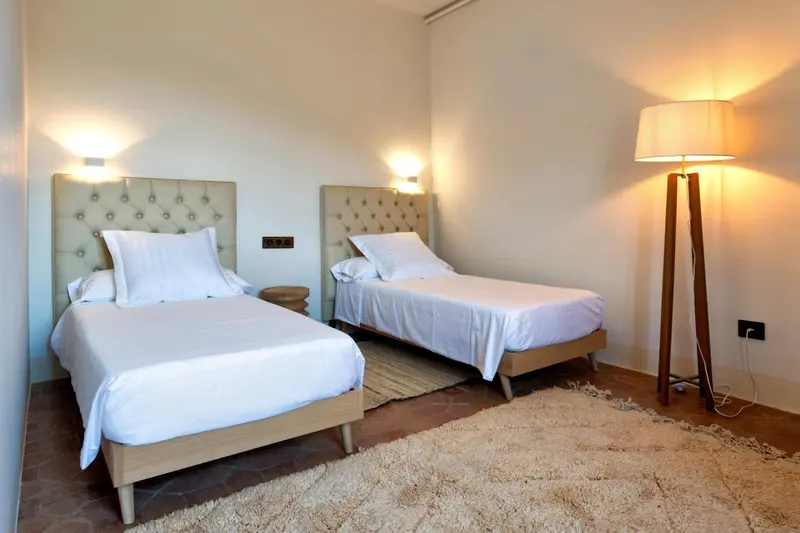 Une chambre lumineuse avec deux lits simples et une décoration sobre.