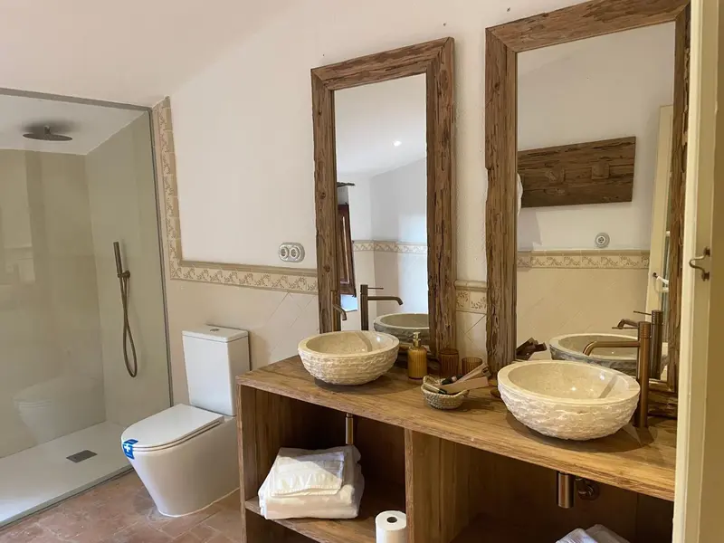 Une salle de bain lumineuse avec deux vasques en pierre et une douche à l'italienne.