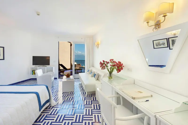 Une chambre lumineuse avec un coin salon et une vue sur la mer.