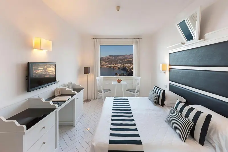 Chambre lumineuse avec un lit double et une vue sur la mer.