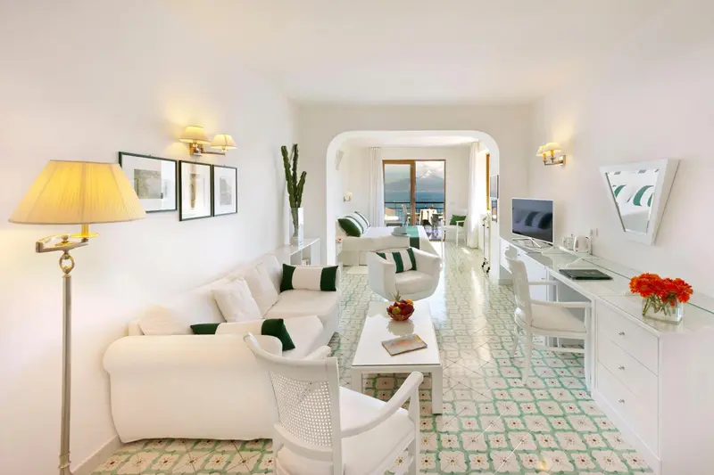 Un salon lumineux avec canapés blancs et une vue sur la mer.