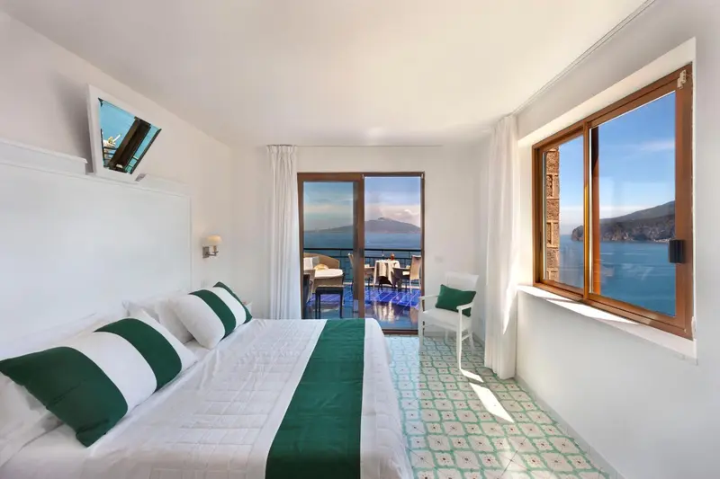 Chambre lumineuse avec un grand lit donnant sur une vue mer.