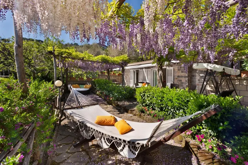Un jardin fleuri abrite des hamacs sous une pergola fleurie.