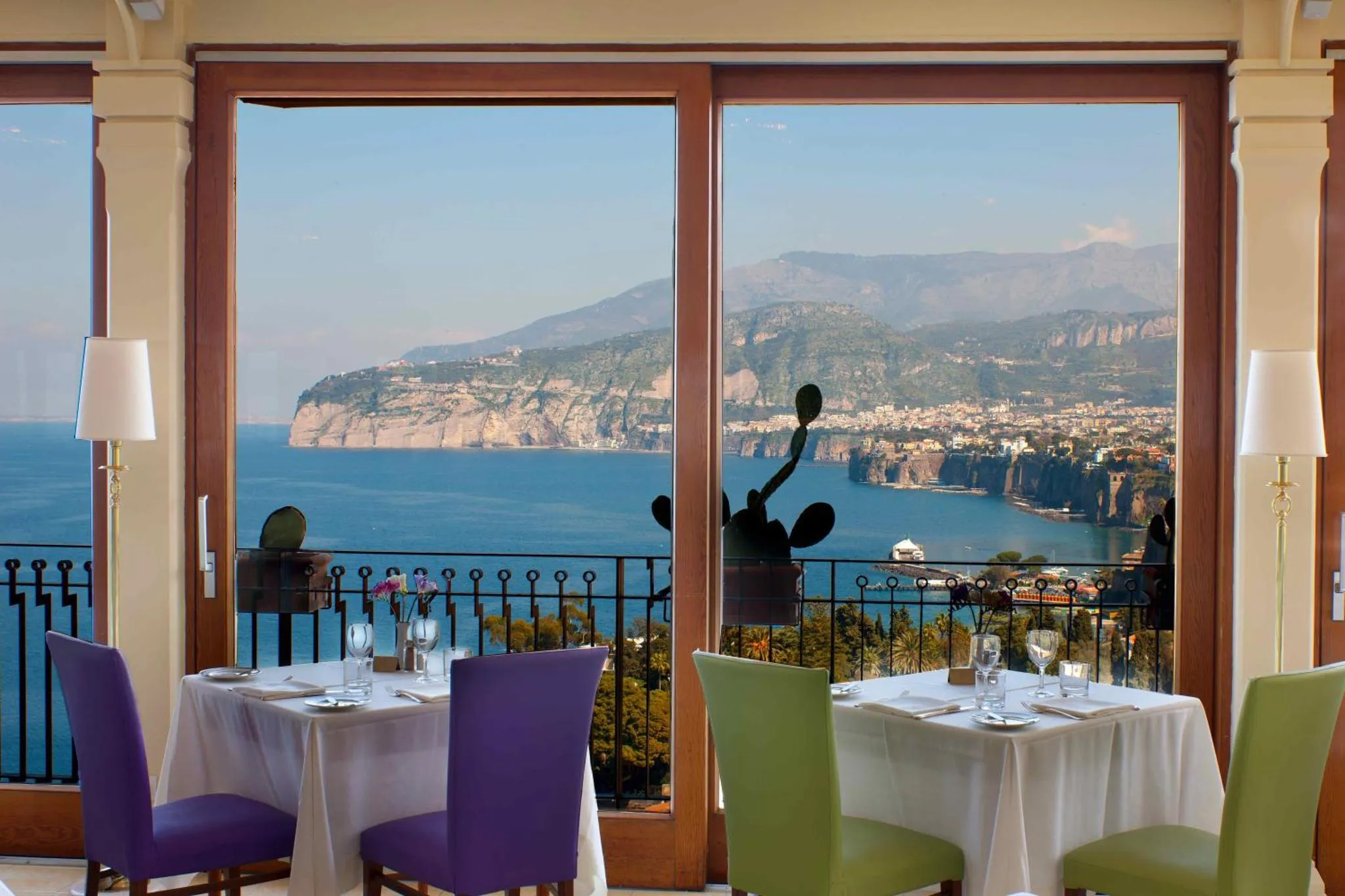 Tables dressées devant une grande baie vitrée donnant sur la mer et les montagnes.