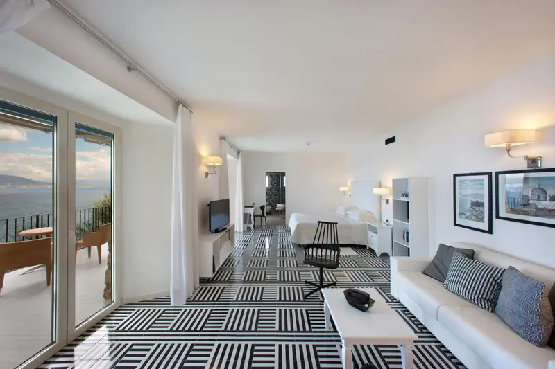 Une piece lumineuse avec un canape et un acces a un balcon avec vue sur la mer.