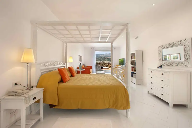 Une chambre lumineuse avec un grand lit à baldaquin et une vue sur la mer.
