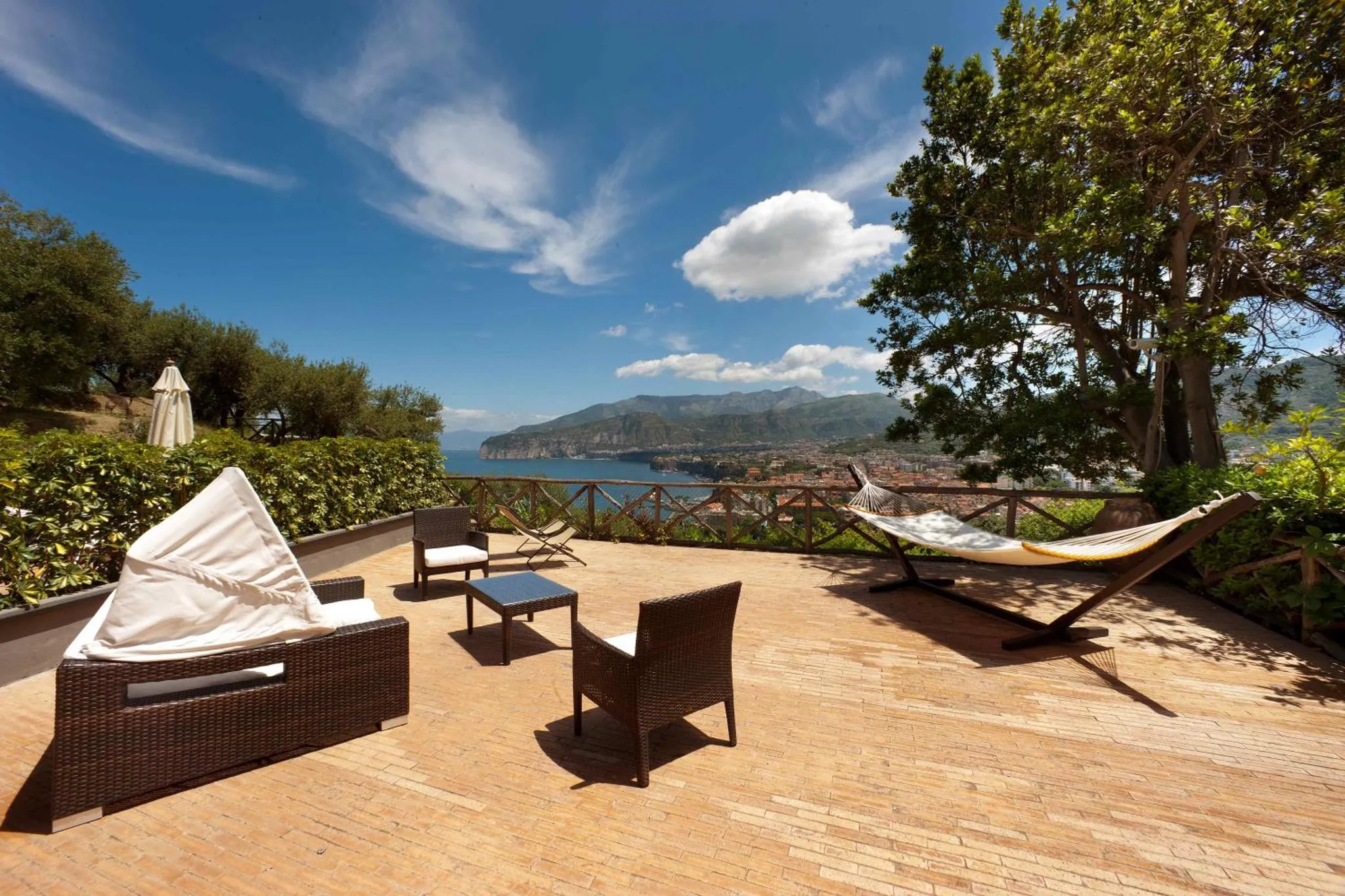 Espace de détente extérieur avec mobilier de jardin et vue sur la mer.