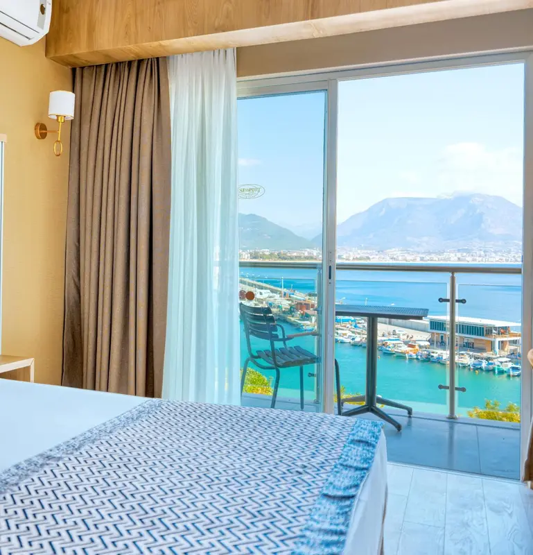 Une chambre lumineuse avec vue sur un port de plaisance et des montagnes.