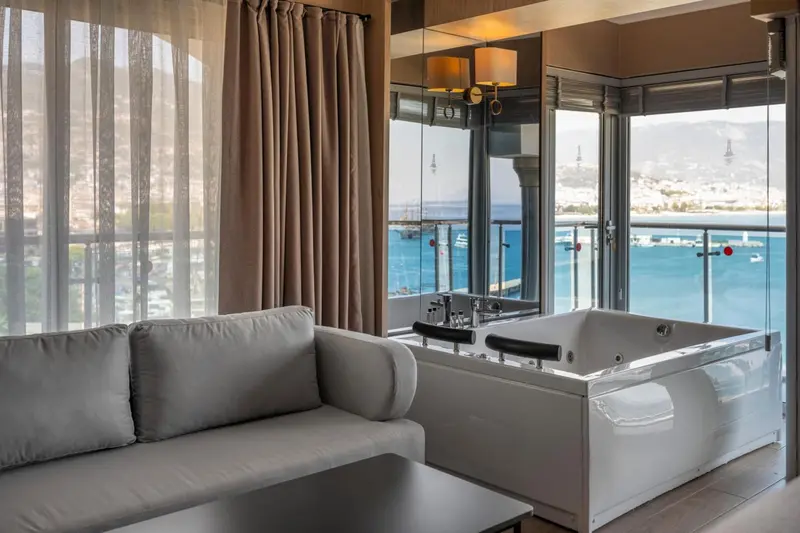 Une chambre avec un coin salon et une baignoire donnant sur la mer.