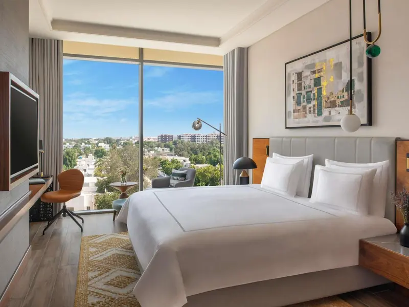 Une chambre lumineuse avec un grand lit et une vue sur la ville.