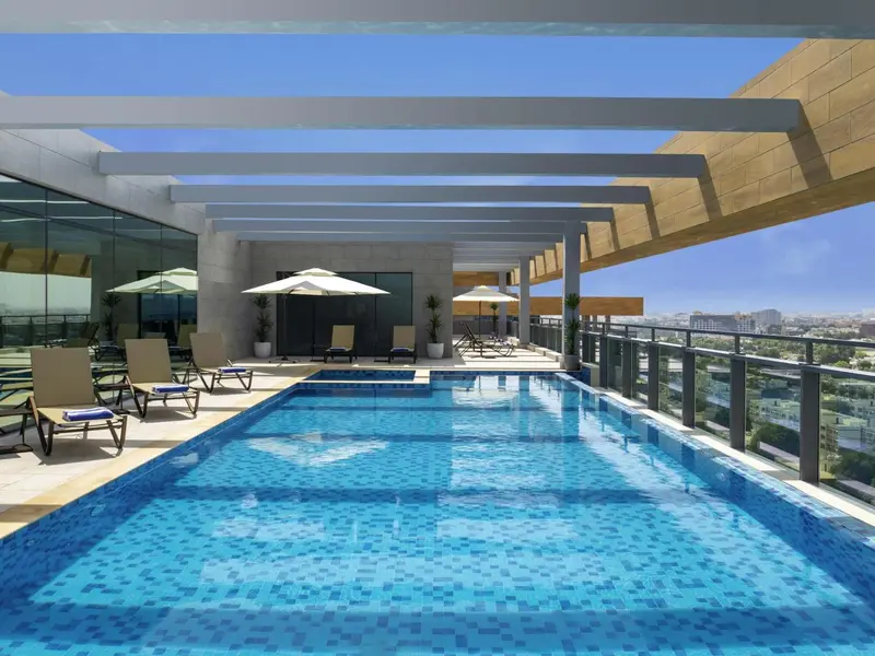 Terrasse avec piscine et chaises longues offrant une vue sur la ville.