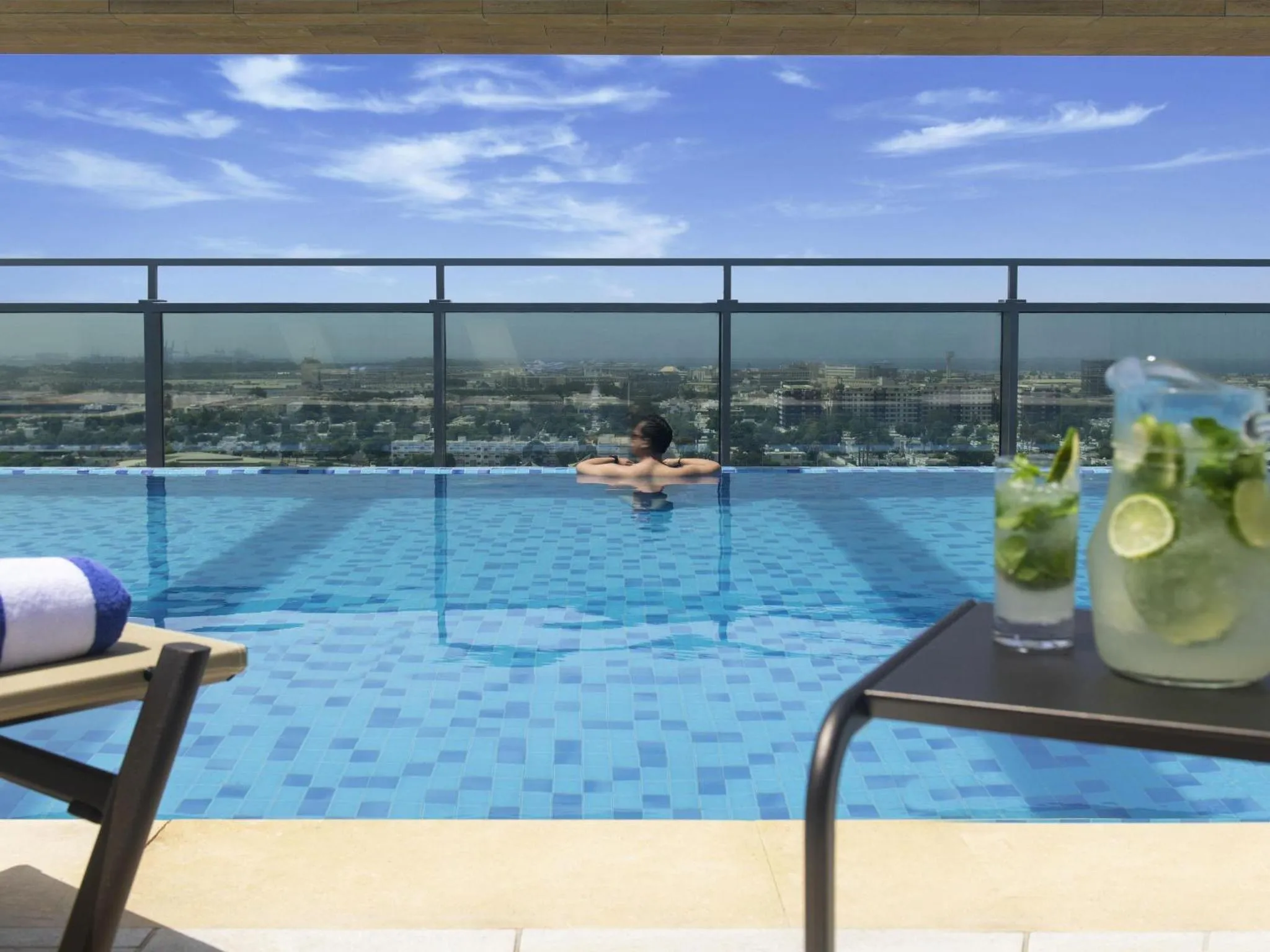 Une personne se détend dans une piscine à débordement avec vue sur la ville.