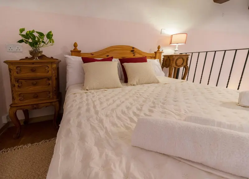 Une chambre lumineuse avec un lit recouvert d'une courtepointe blanche et de coussins.