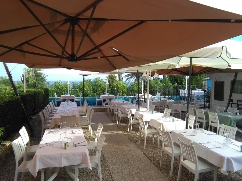 Tables dressées en terrasse avec parasols et vue sur la mer.