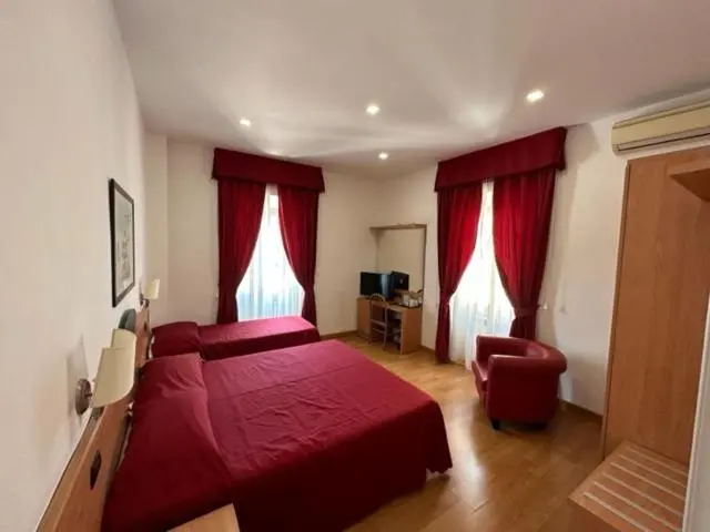 Chambre avec deux lits simples et un fauteuil rouge.