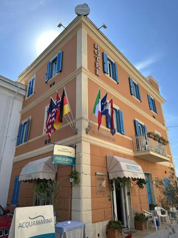 Façade d'un bâtiment orange à balcons bleus avec des drapeaux et une marquise.