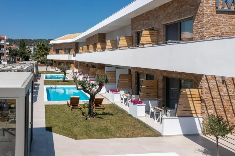 Vue aérienne d'un bâtiment moderne avec des balcons et une piscine entourée d'un jardin soigné.