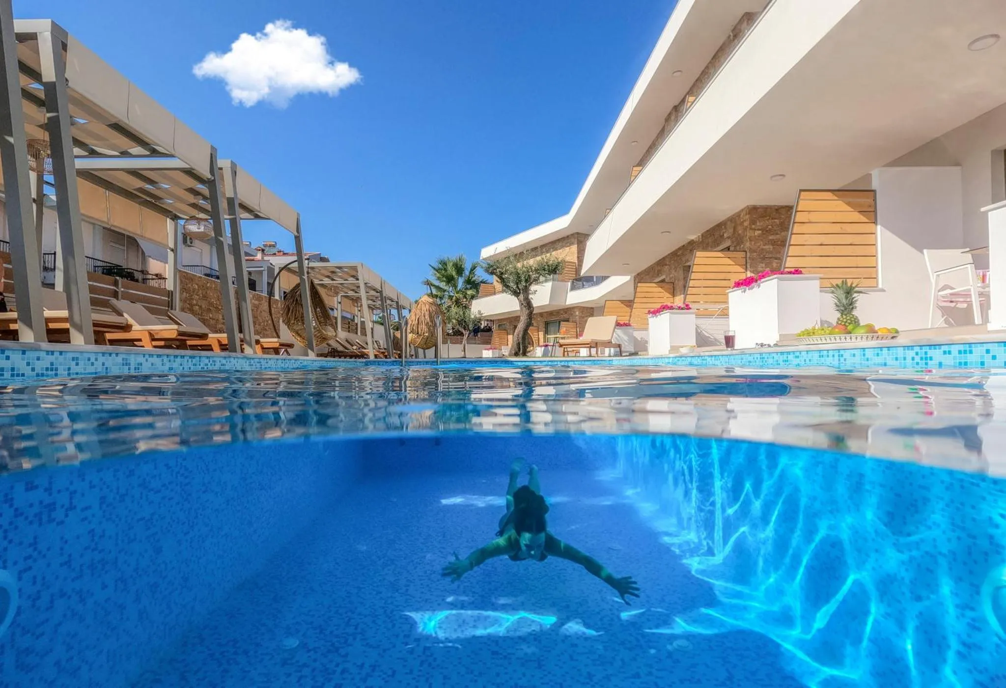 Vue sur une piscine avec une personne nageant en contrebas et des transats sur le bord.
