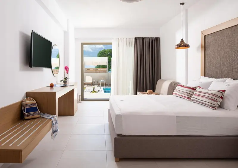 Une chambre lumineuse avec un grand lit et un accès à une terrasse avec piscine.