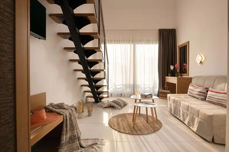Espace de vie intérieur lumineux avec canapé et escalier métallique.