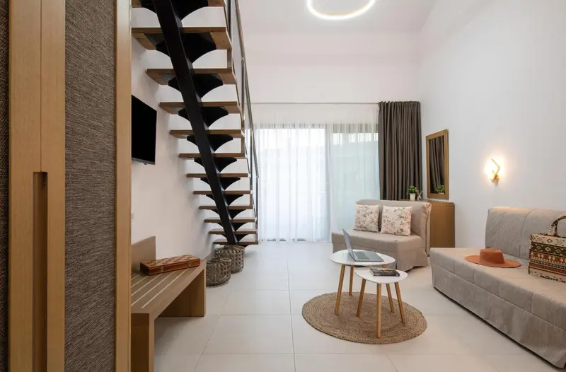 Espace de vie intérieur lumineux avec canapé et escalier métallique.