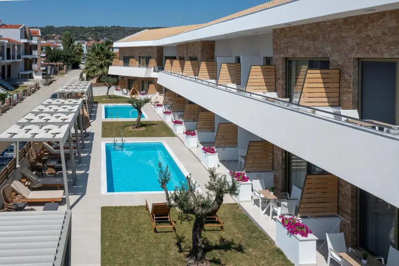 Vue aérienne d'un complexe hôtelier blanc et beige avec piscine et végétation.