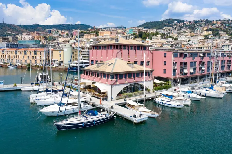 Vue aérienne d'un port de plaisance avec des bâtiments colorés en arrière-plan.