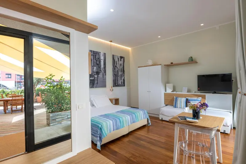 Une chambre lumineuse avec un lit et un coin repas près d'une baie vitrée.