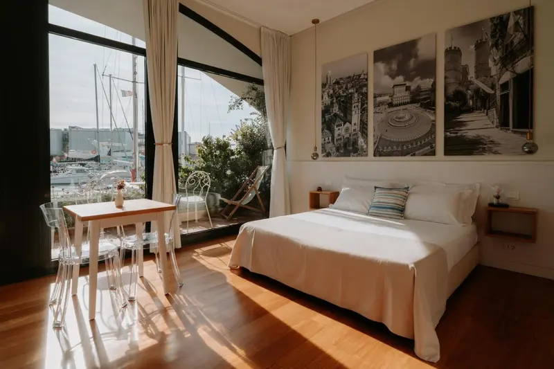 Une chambre lumineuse avec un lit et une table près d'une fenêtre donnant sur un port de plaisance.