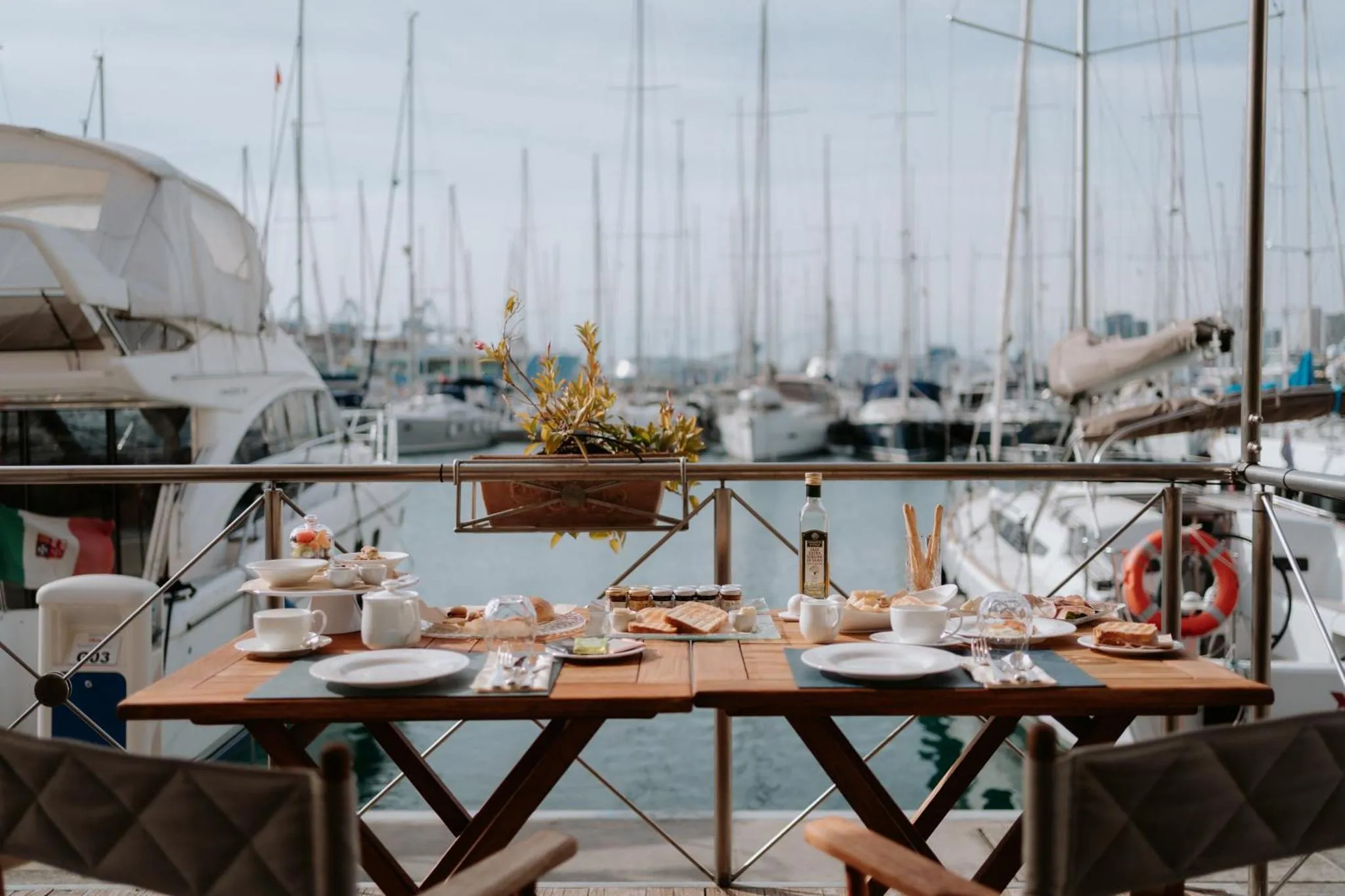 Une table est dressée avec des couverts et de la nourriture sur une terrasse en bord de mer.