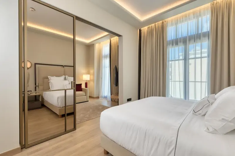 Une chambre lumineuse avec un grand lit et un dressing miroir.