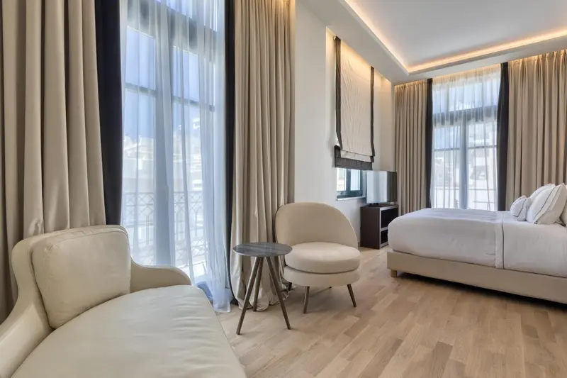 Une chambre lumineuse avec un coin salon et un lit double.