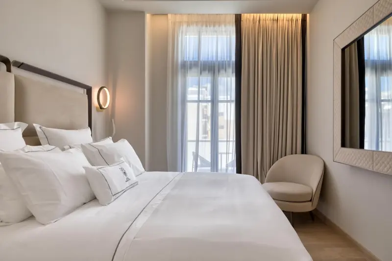 Une chambre lumineuse avec un grand lit et un fauteuil.