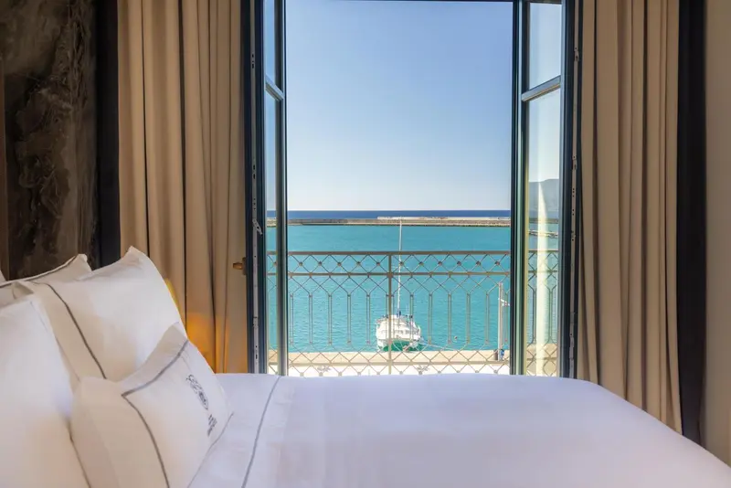 Vue sur la mer depuis une chambre avec un balcon en fer forgé.