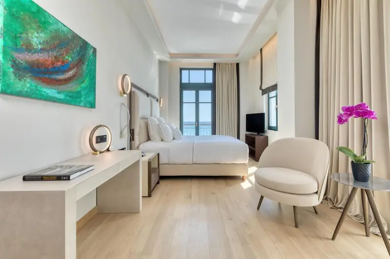 Une chambre lumineuse avec un lit double et un coin salon.